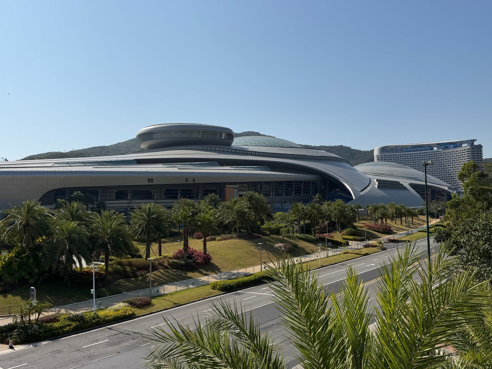 The silver saucer-shaped Chimelong Spaceship building rising behind palm gardens at Chimelong International Ocean Resort on Hengqin