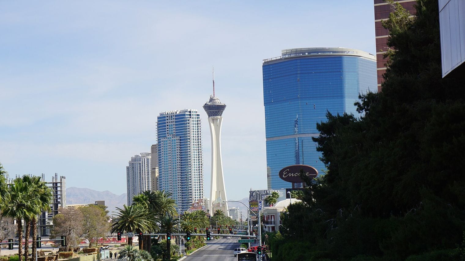 The Las Vegas Strip looking north toward the STRAT tower, with the blue glass of Encore at Wynn Las Vegas rising on the right