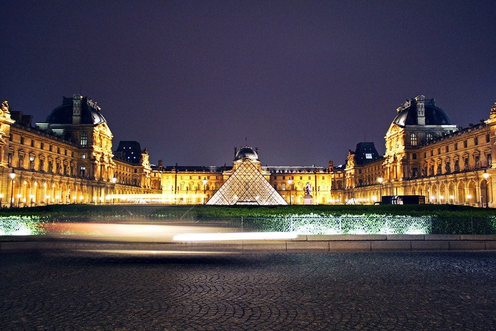 The illuminated glass pyramid standing in the floodlit courtyard of the Louvre palace in Paris after dark