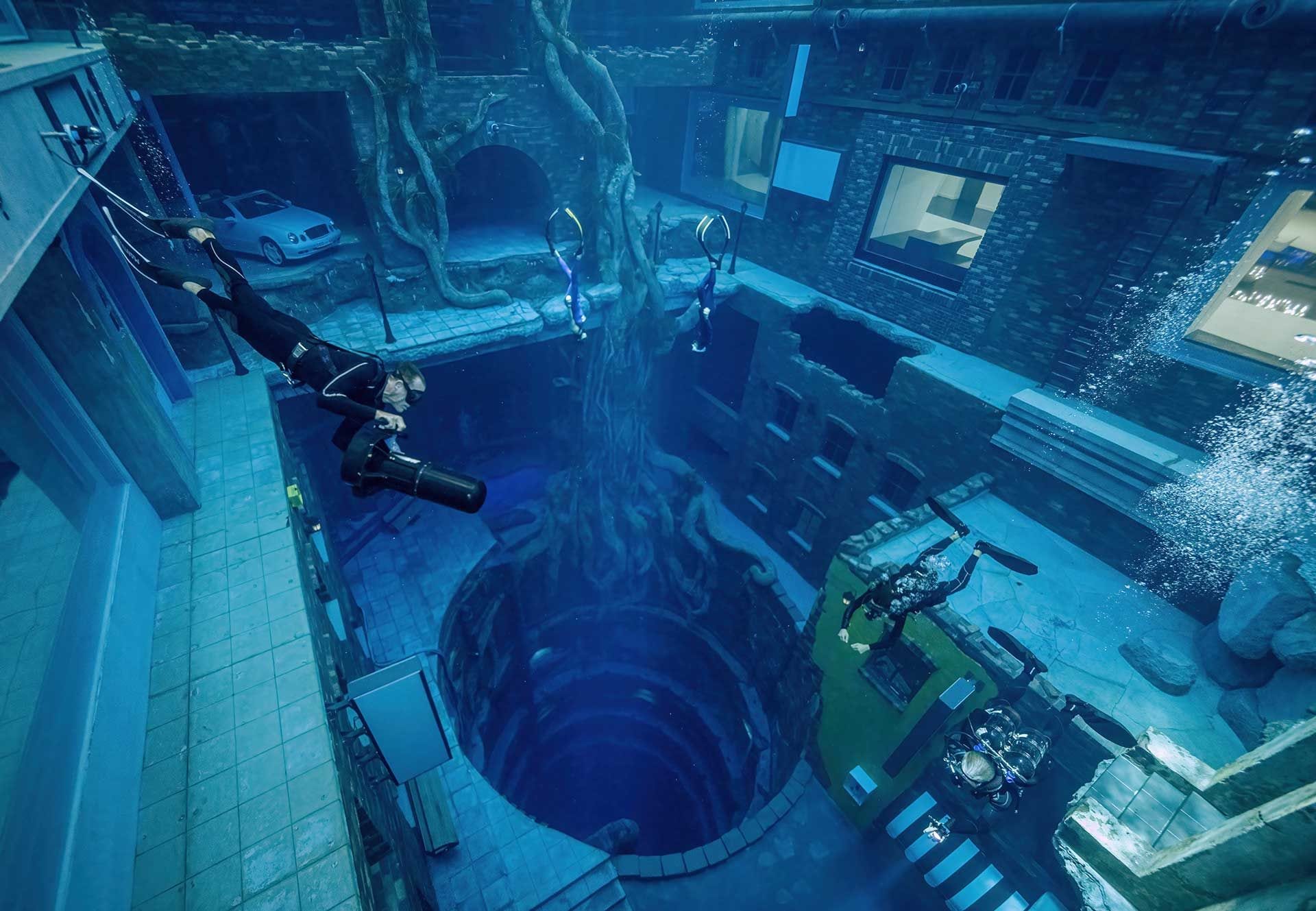 Divers gliding over the sunken-city streets and the deep circular shaft inside the Deep Dive Dubai pool in Nad Al Sheba, Dubai