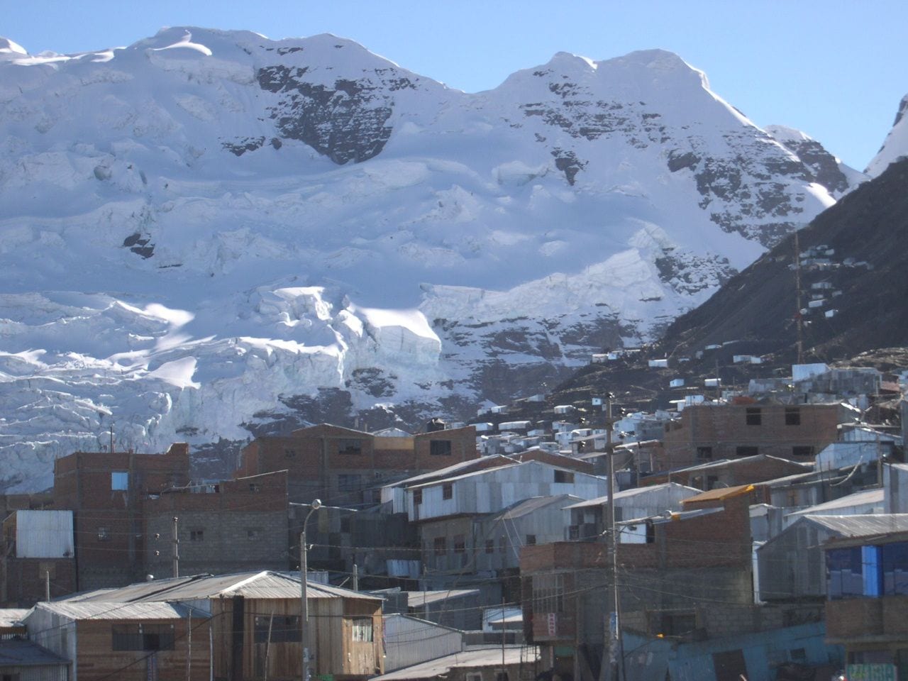 Brick and tin-roofed houses of La Rinconada, the gold-mining town in Puno, Peru, crowded below a glacier-clad Andean peak