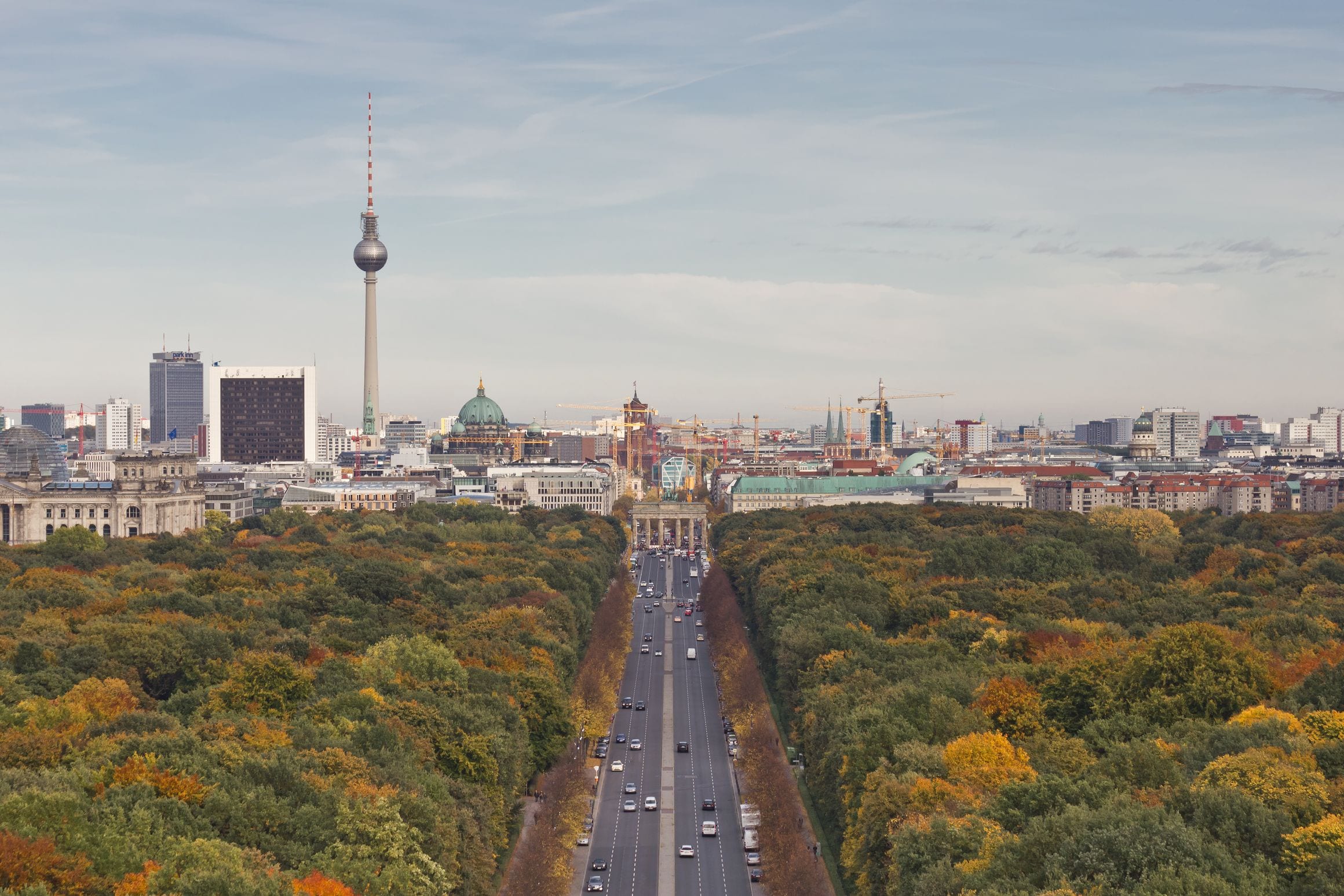 The view east from the Victory Column across the autumn Tiergarten to the Brandenburg Gate, with the Fernsehturm and Berlin Cathedral beyond