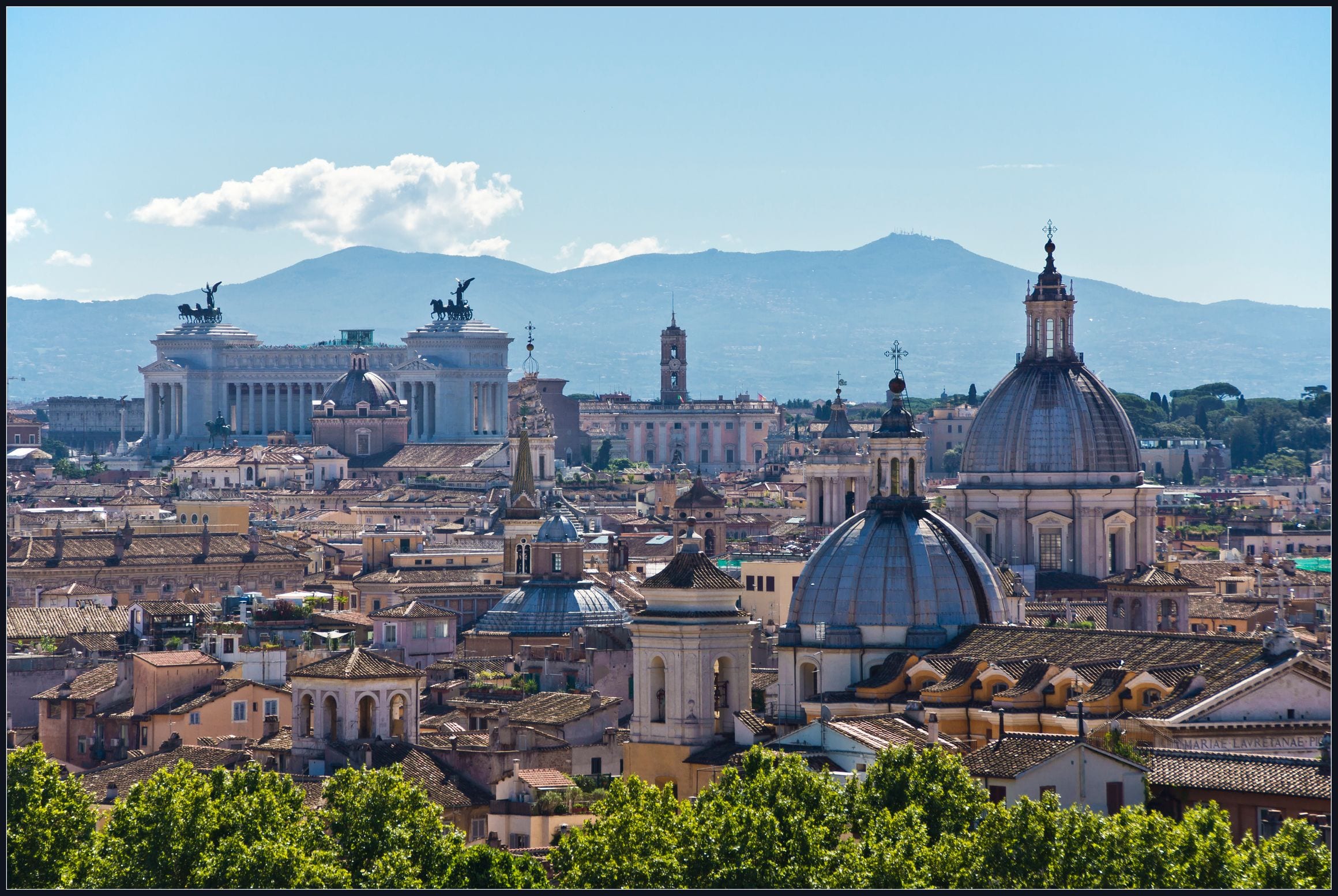 Rome rooftops and church domes across the historic centre, with hills on the horizon