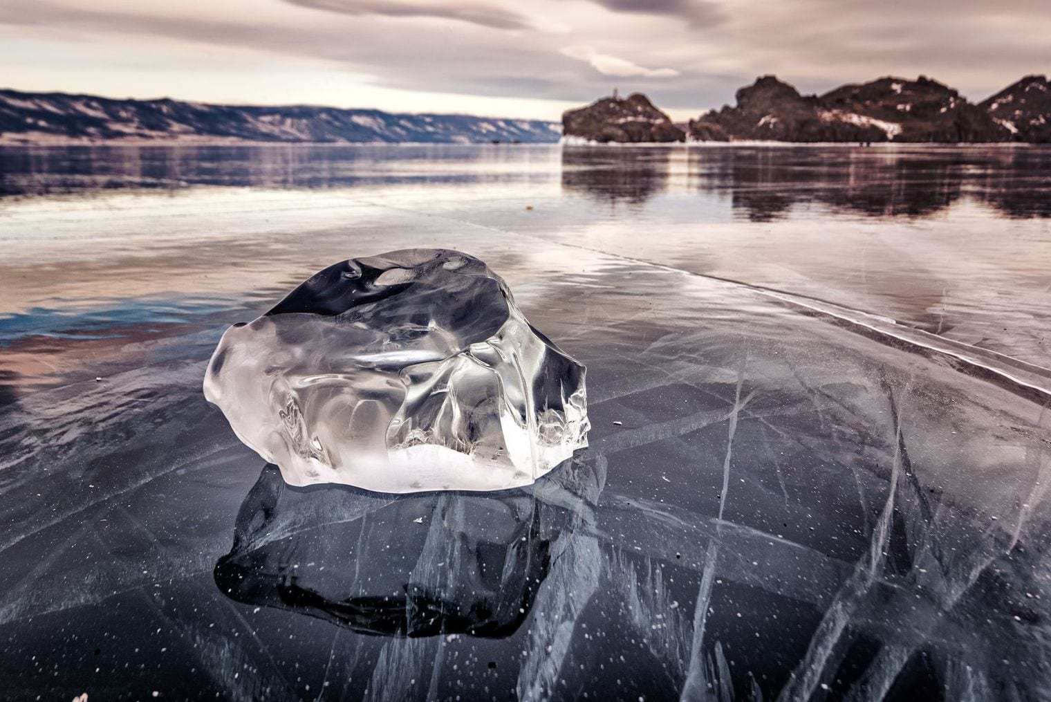 Slabs of turquoise pressure ice piled along the frozen surface of Lake Baikal under a pale winter sky.