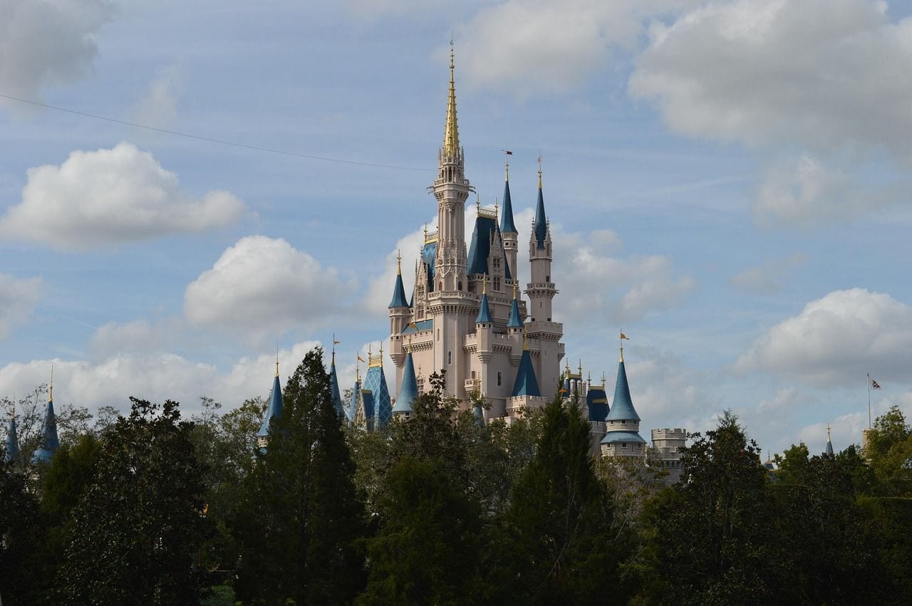 Cinderella Castle rising above a line of trees under a blue sky scattered with cloud