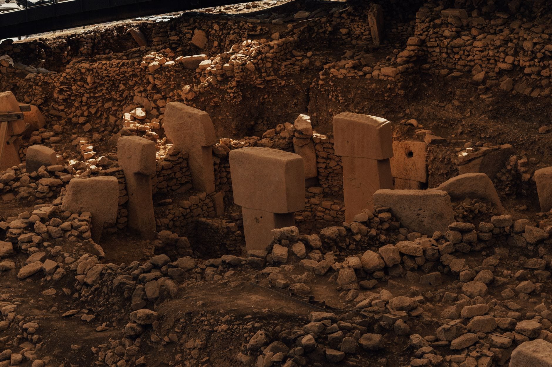 Massive carved T-shaped limestone pillars rising from the excavated stone-walled enclosures of Göbekli Tepe near Şanlıurfa, Turkey