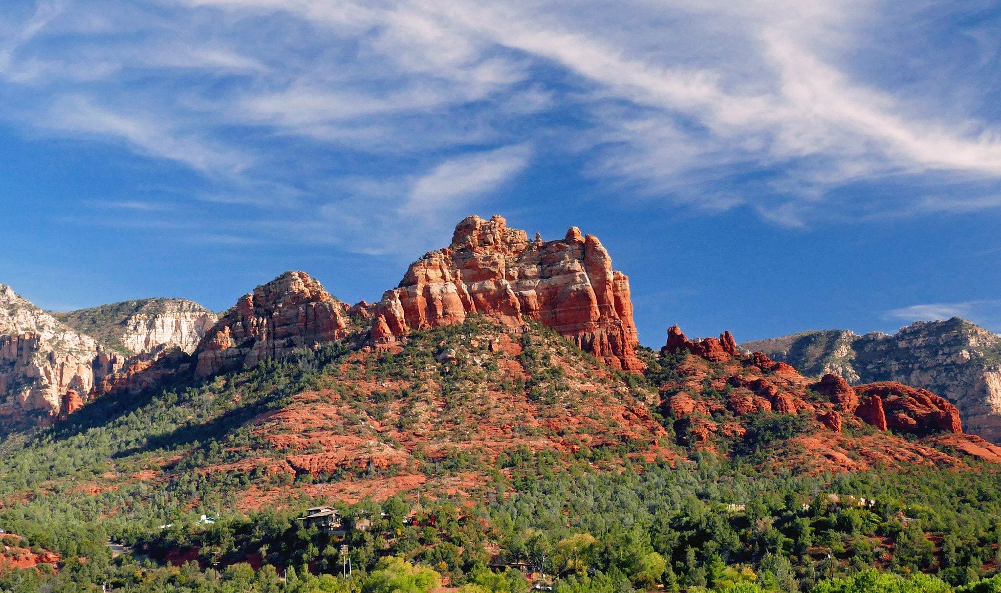Red sandstone buttes rising above juniper-covered hillsides near Sedona, Arizona
