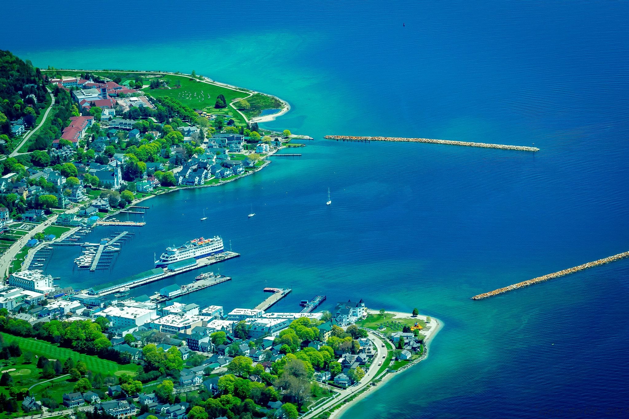 Aerial view of Mackinac Island, Michigan, with its harbor, town waterfront and breakwaters on turquoise Lake Huron water