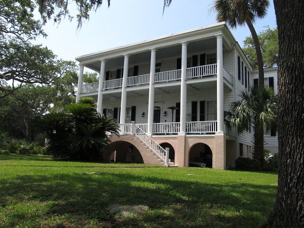A white antebellum house with double-tiered porches among palmettos and live oaks in the historic district of Beaufort, South Carolina