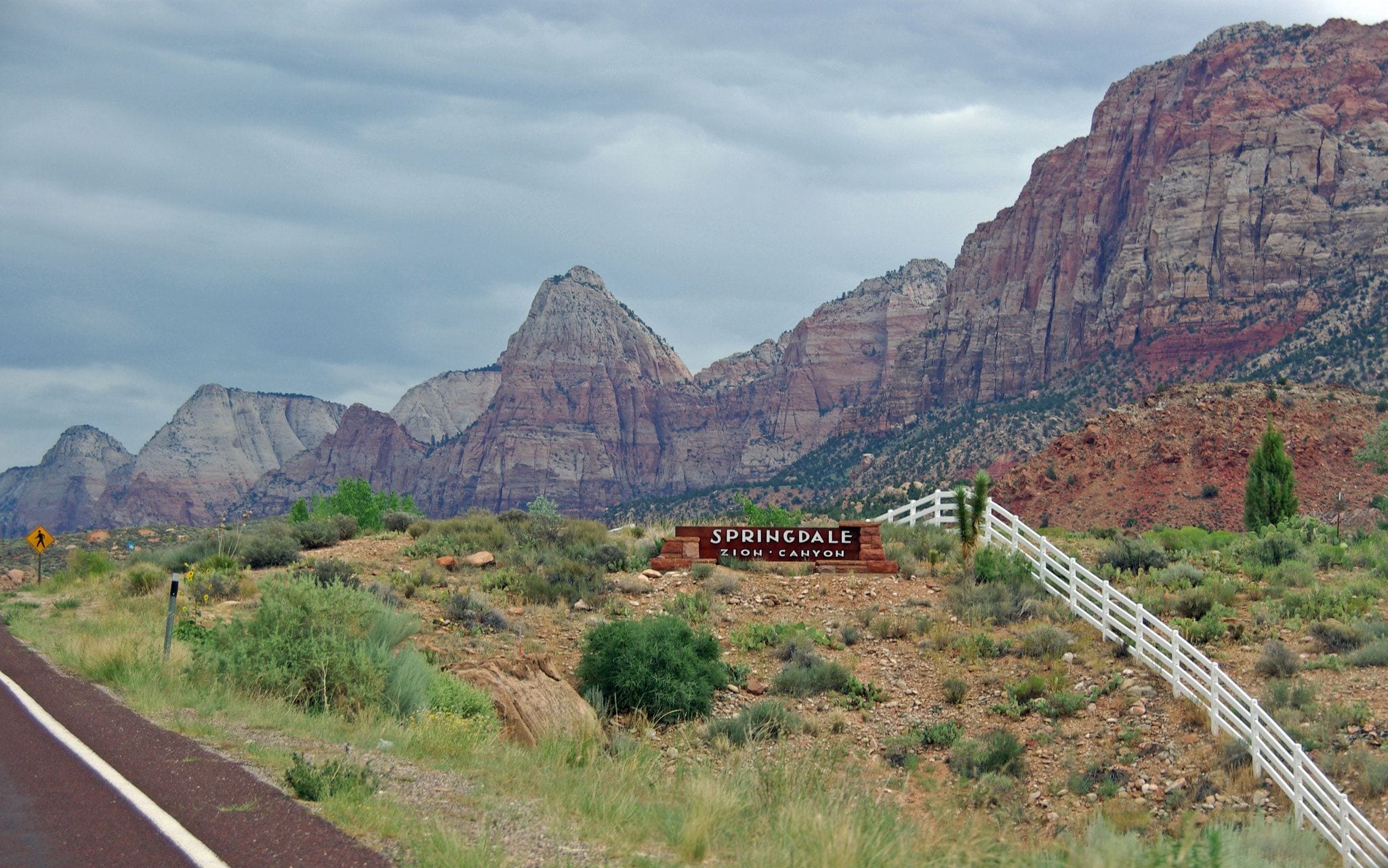 Welcome to Springdale sign beneath red sandstone cliffs at the edge of Zion Canyon, Utah