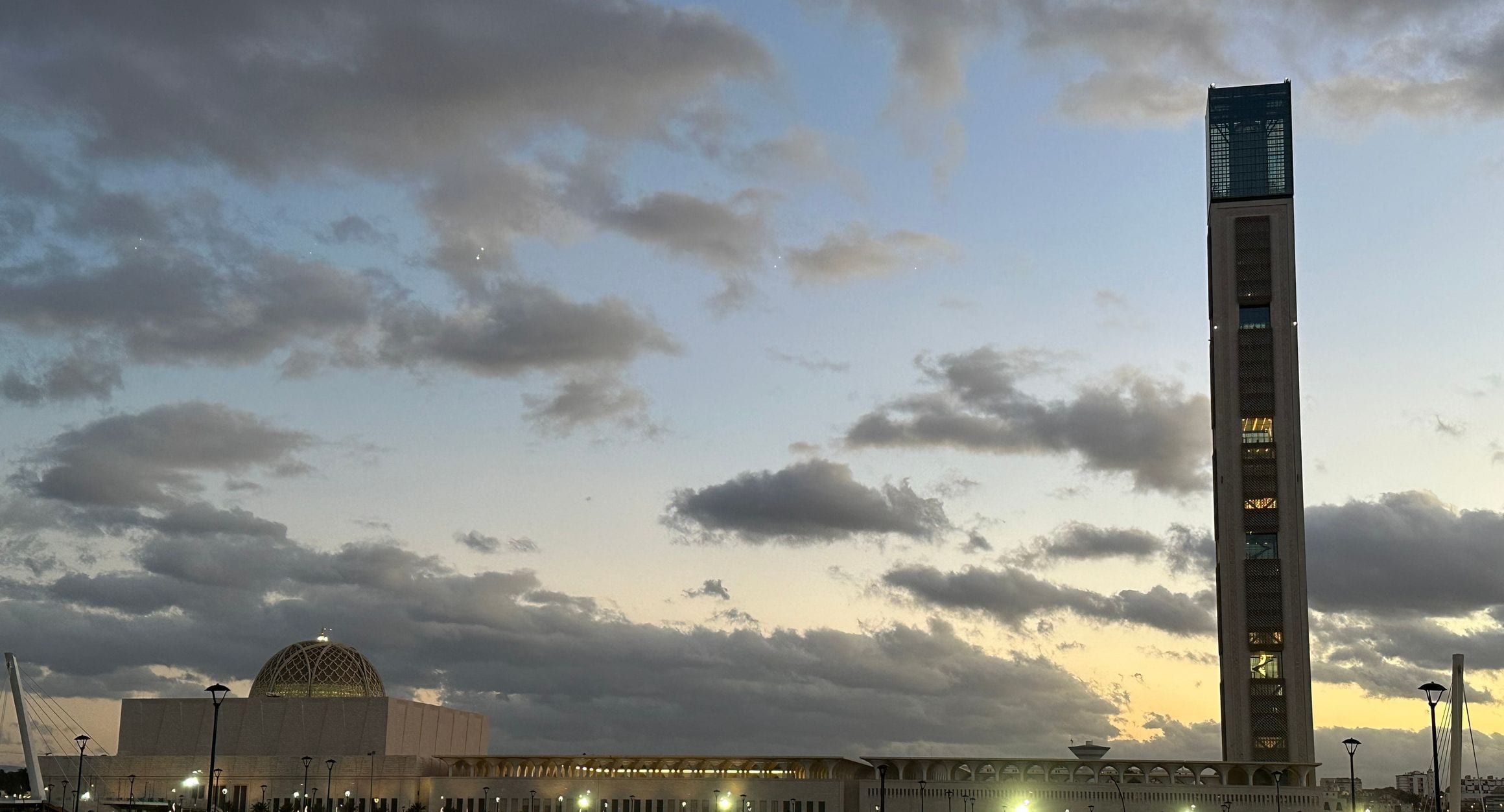 The soaring minaret and latticed dome of Djamaa el Djazaïr, the Great Mosque of Algiers, under a cloudy dusk sky in Mohammadia