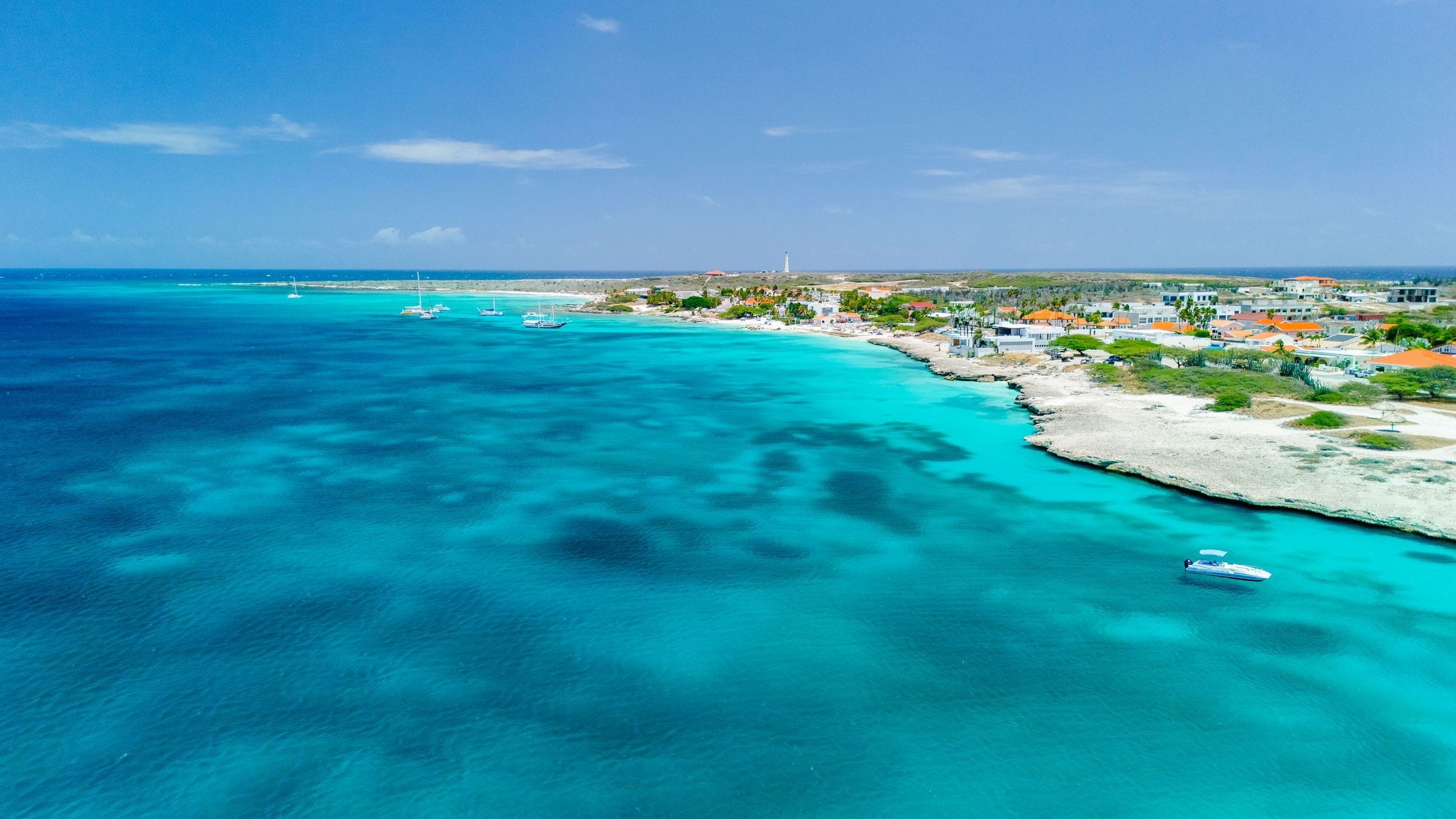 Aerial view of Aruba’s turquoise coastline, where shallow reef water meets a low sandy shore