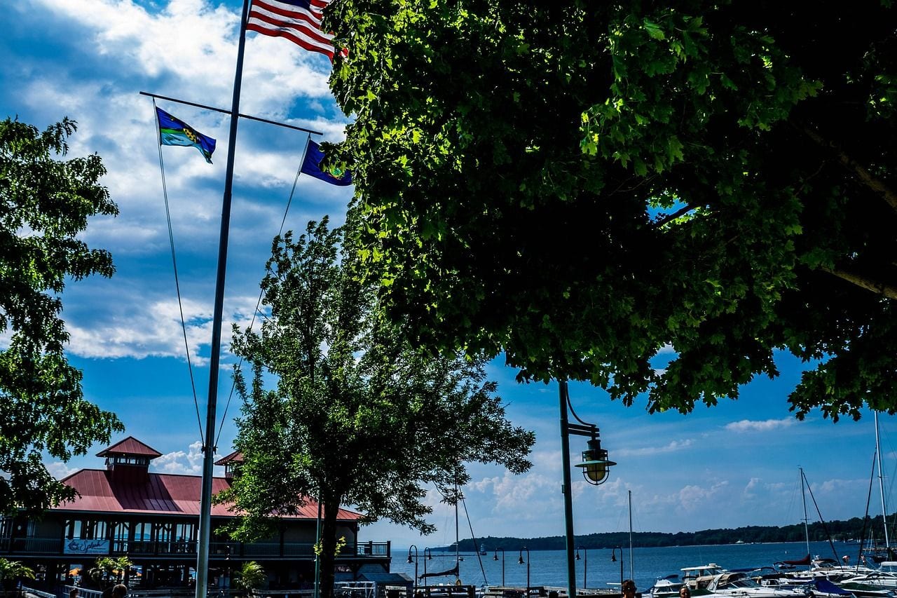 Flags flying beside the Burlington, Vermont waterfront, with the boathouse and Lake Champlain beyond the trees