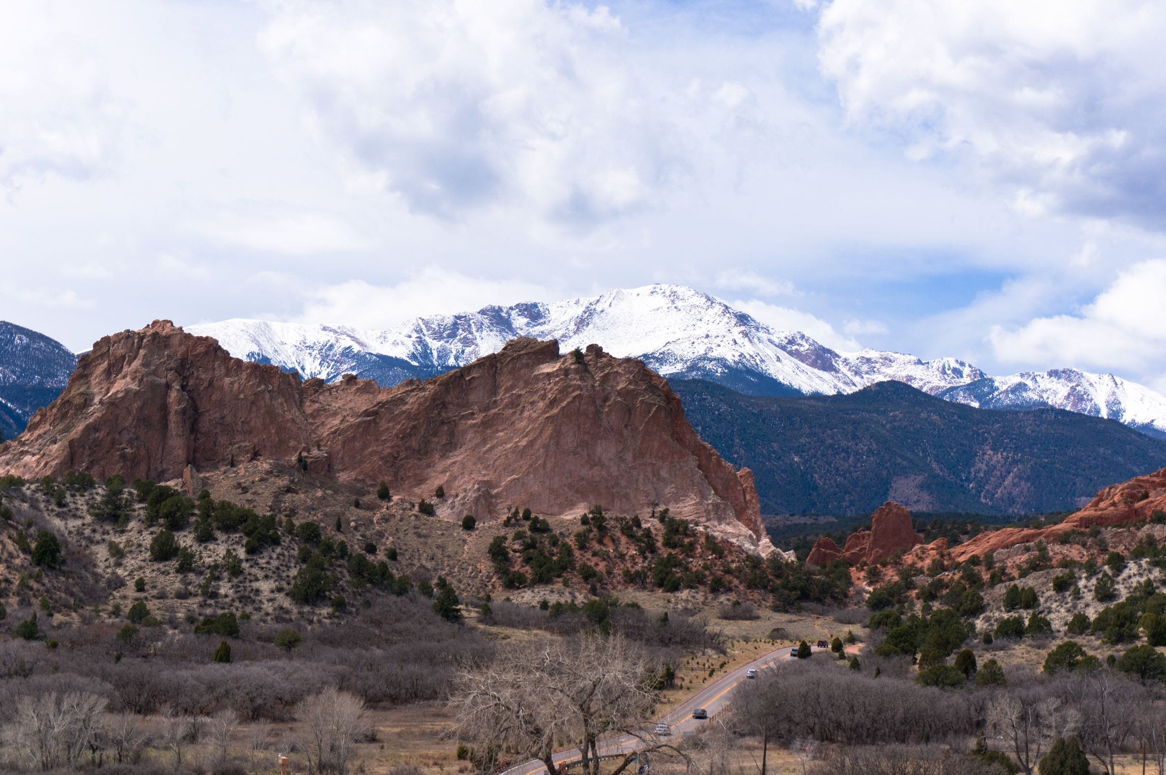 Red sandstone fins of Garden of the Gods with snow-capped Pikes Peak rising behind them