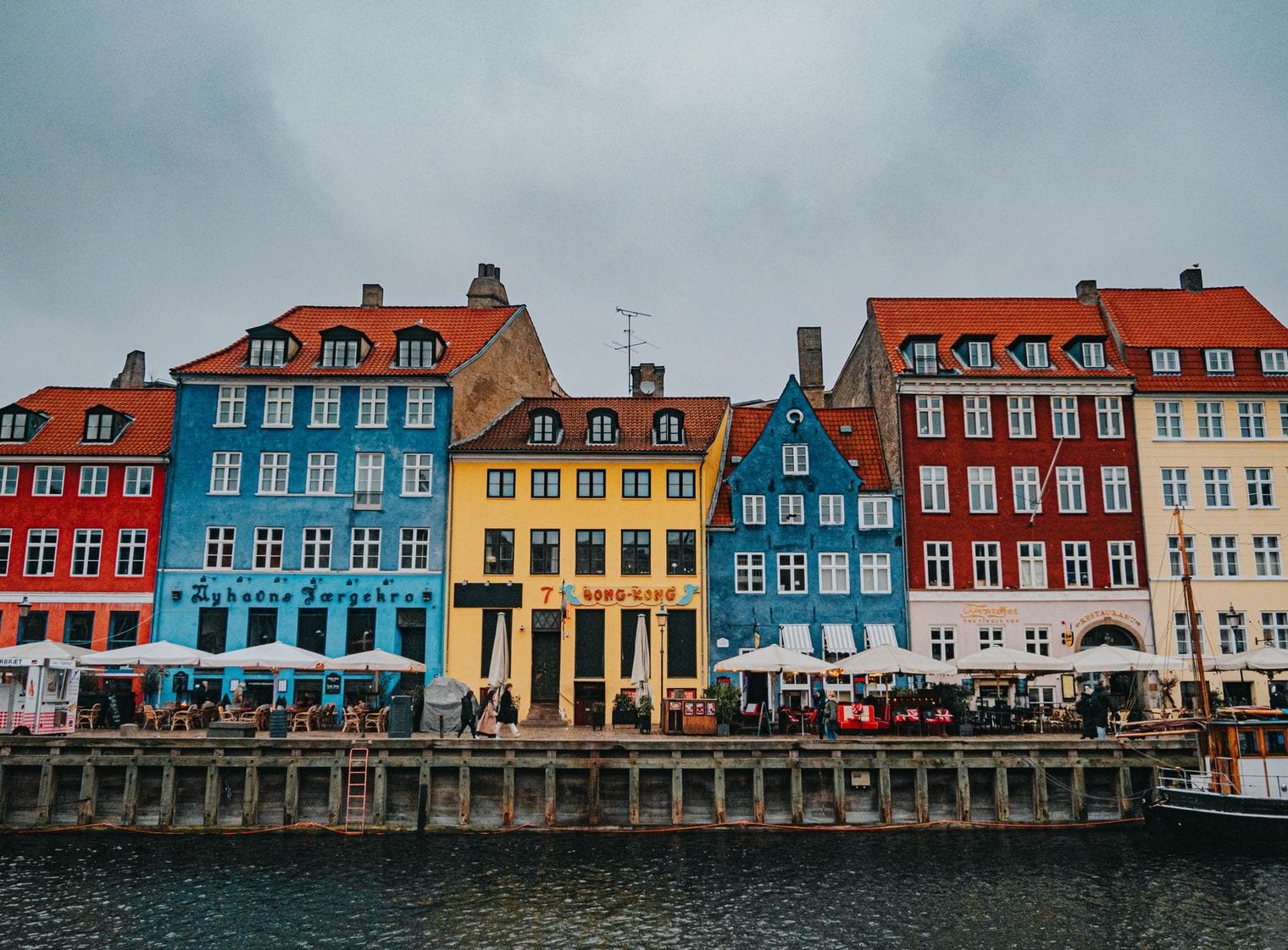Colourful gabled townhouses and a moored wooden sailing ship along the Nyhavn canal quay in Copenhagen