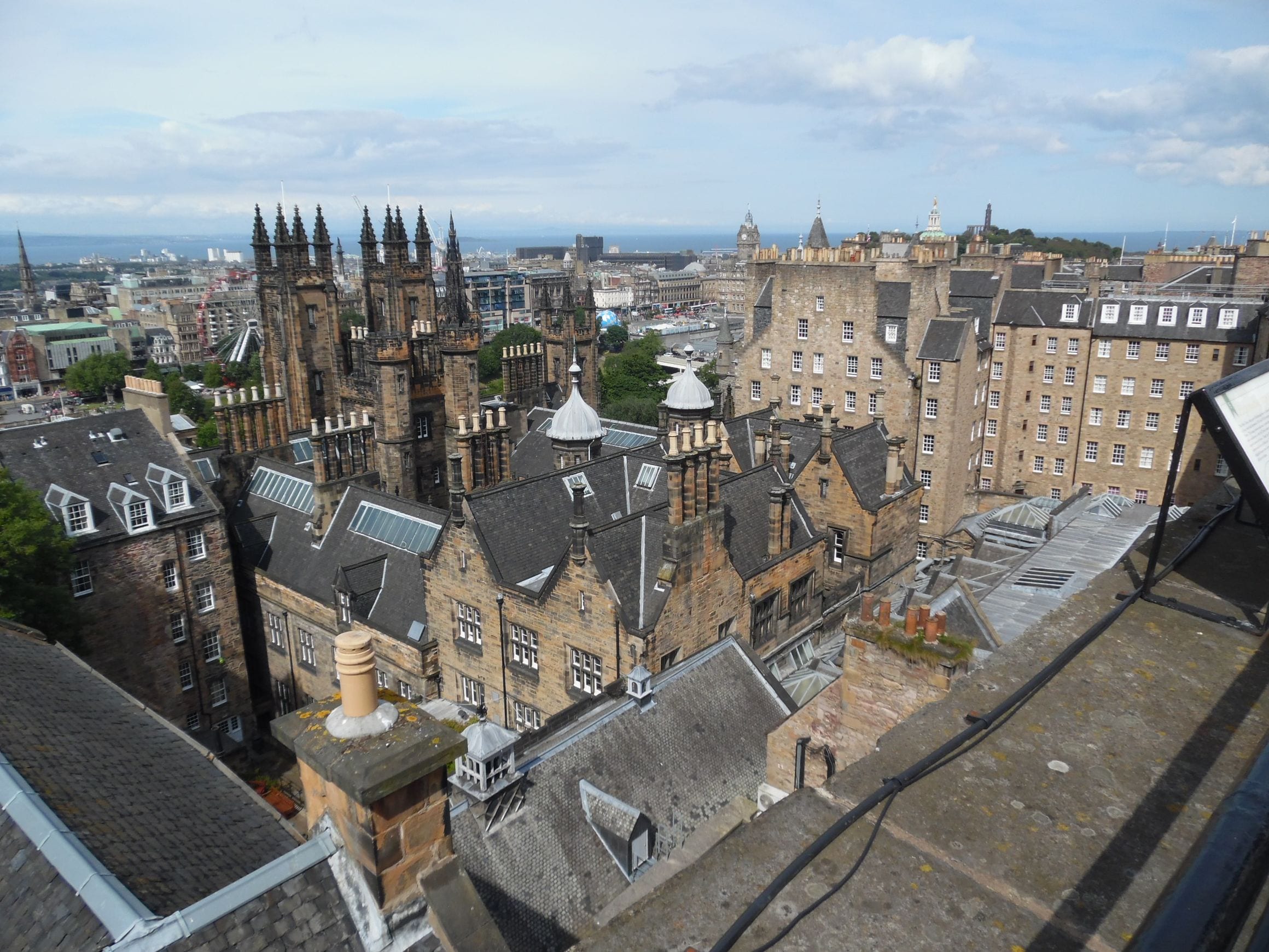 Rooftops of Edinburgh Old Town seen from Castle Hill, with the Balmoral clock tower, the Scott Monument and Calton Hill beyond and the Firth of Forth on the horizon