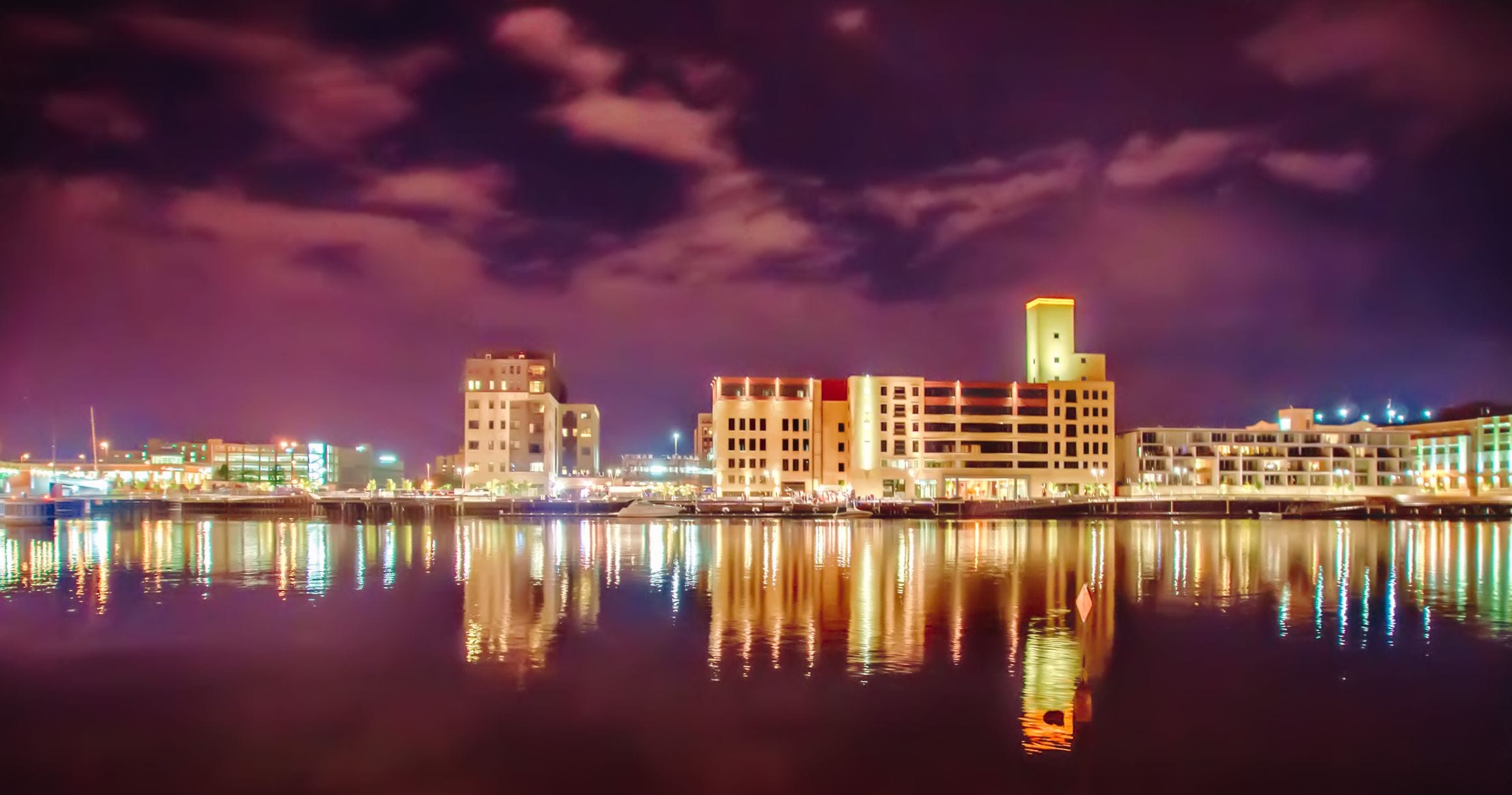 Downtown Green Bay at night, its lit waterfront buildings reflected in the Fox River