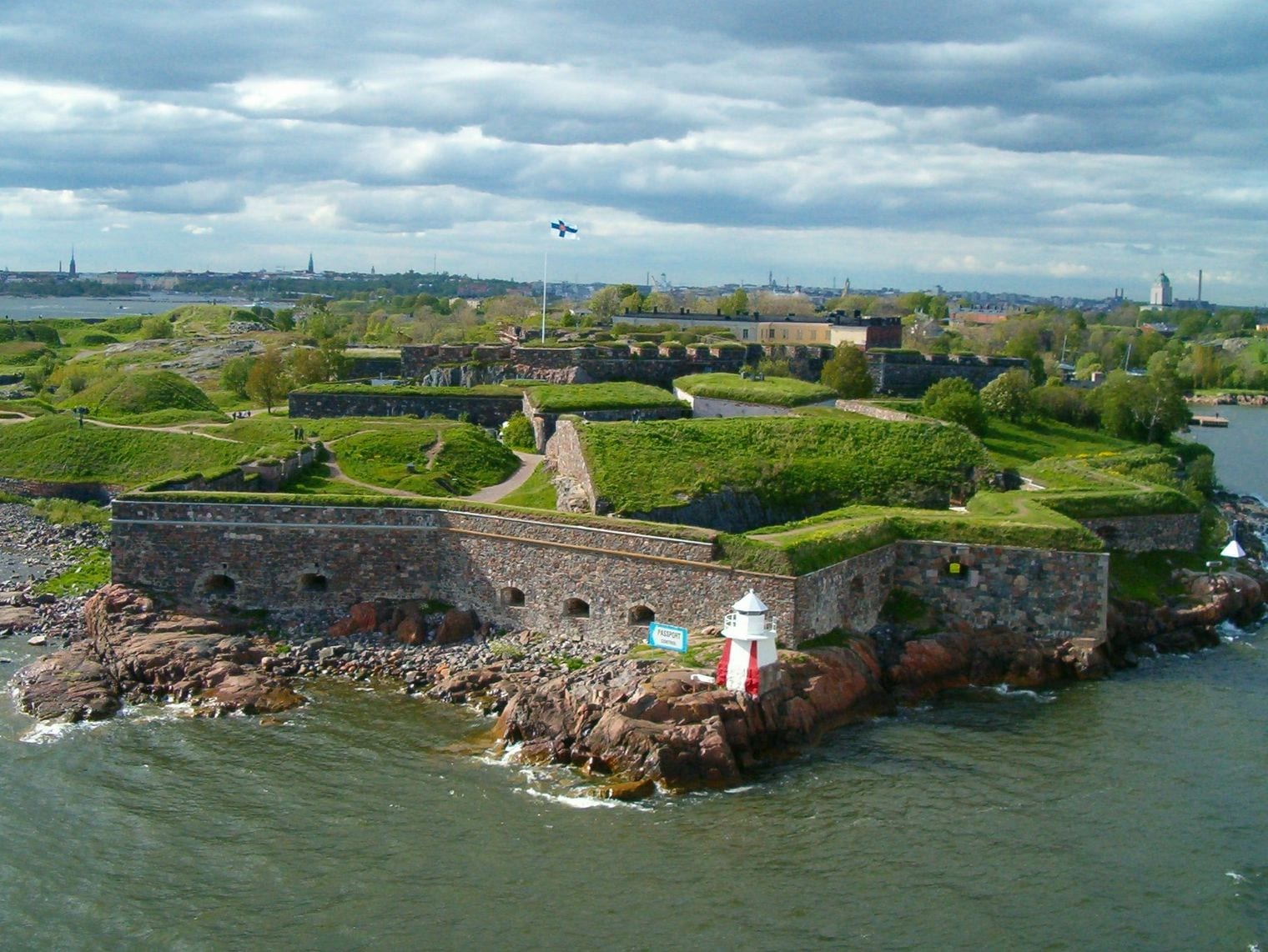 Aerial view of the star-shaped bastions of Suomenlinna sea fortress, its grass-topped ramparts ringed by the Baltic with Helsinki on the horizon.