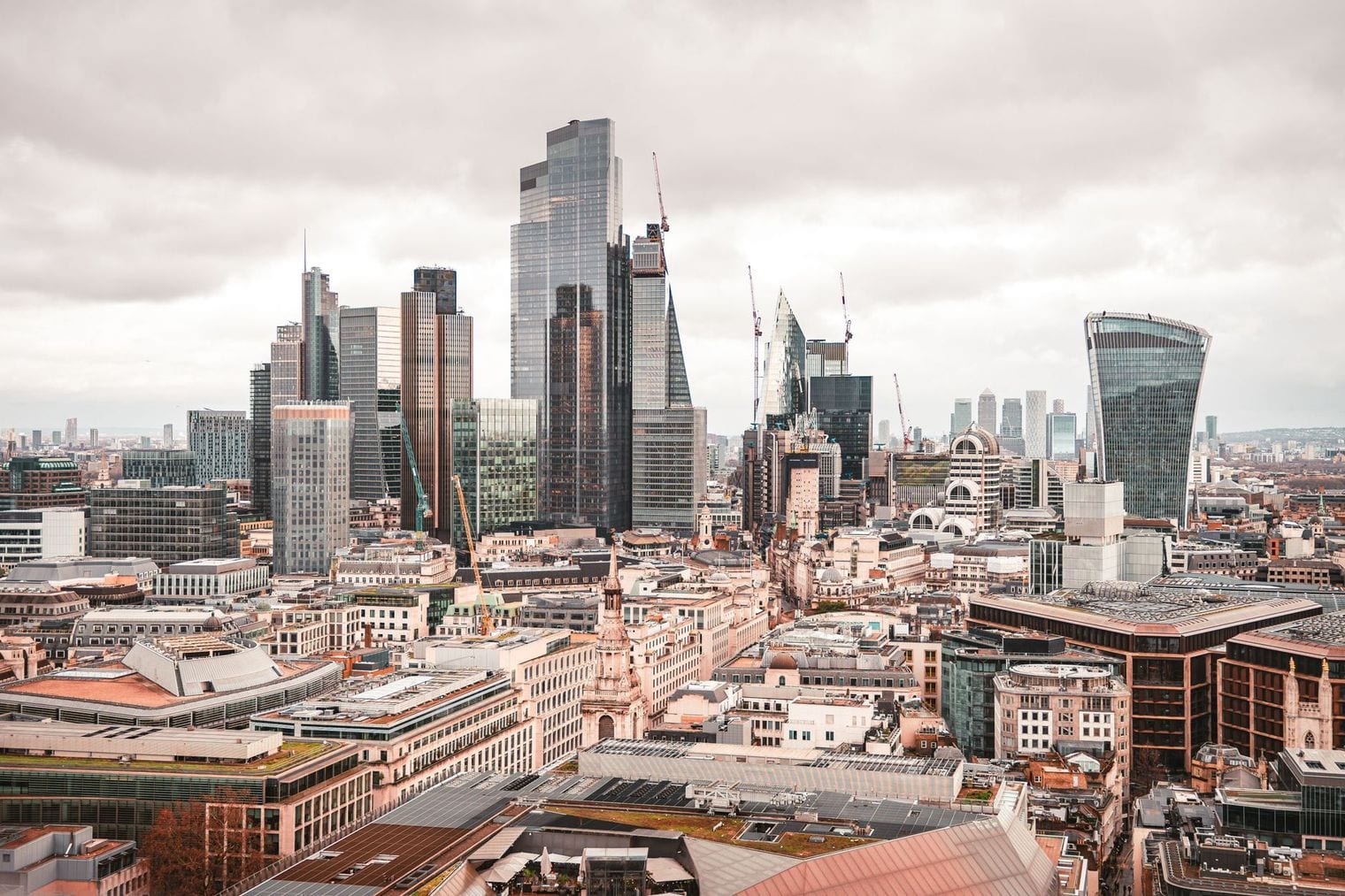 The City of London skyline seen from above, its cluster of glass towers rising over older rooftops beside the Thames