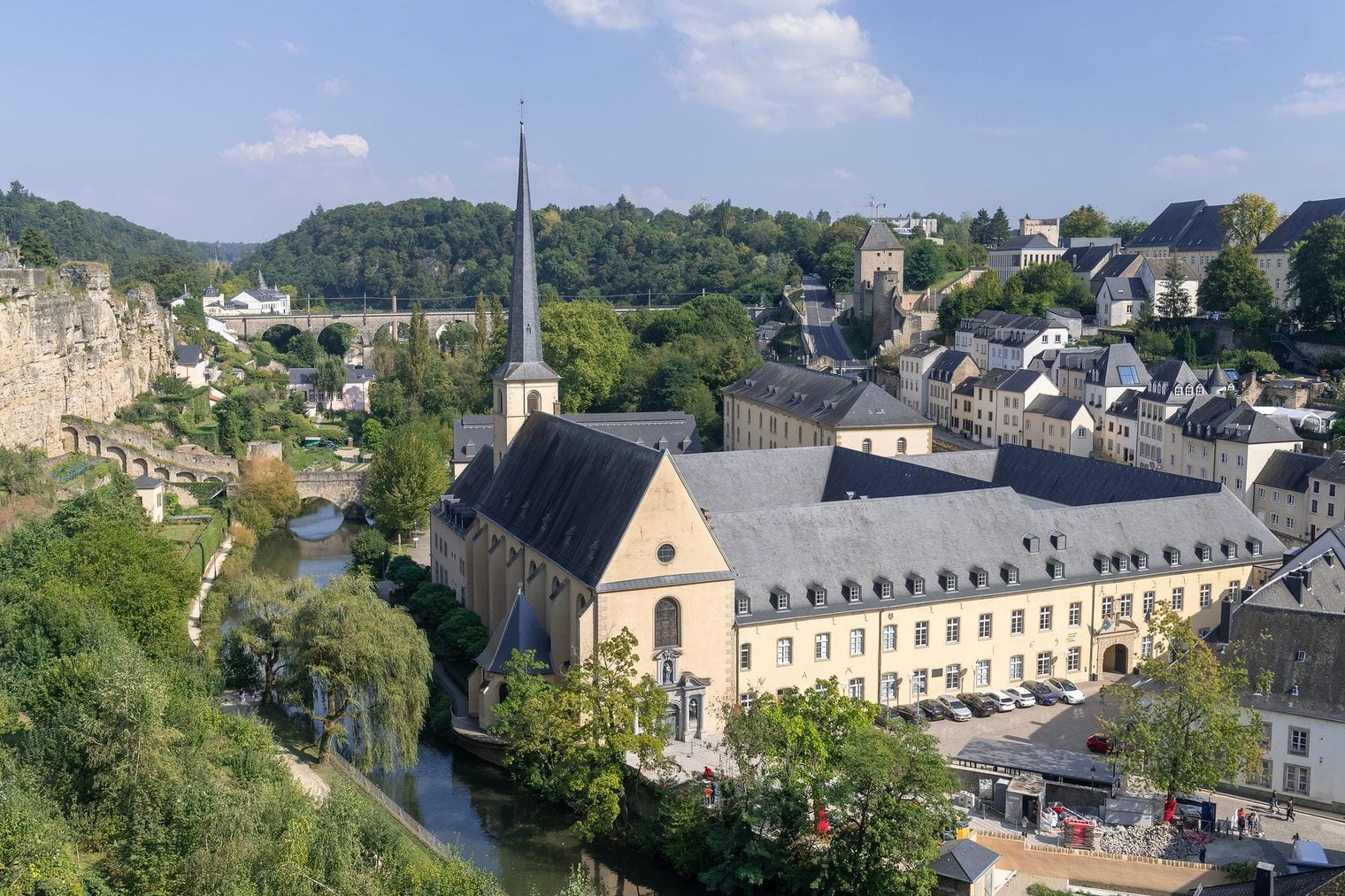 Stone houses of the Grund along the Alzette below Luxembourg City fortress cliffs, with Neumunster Abbey and the old ramparts above