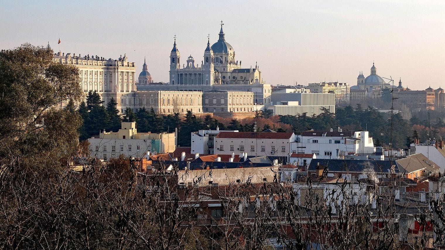 The Royal Palace and the dome and towers of Almudena Cathedral rising above the rooftops of central Madrid in late afternoon light
