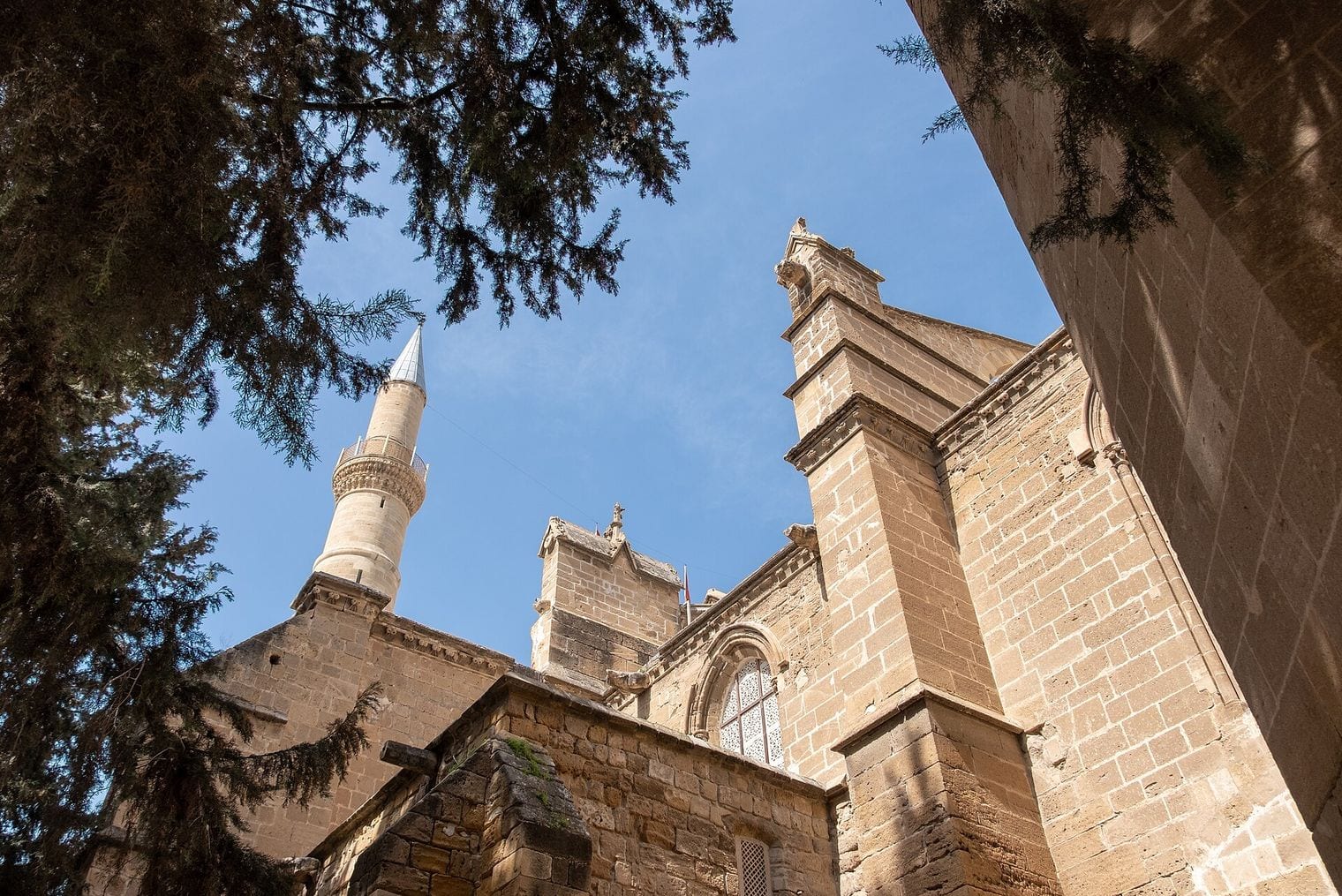 The Ottoman minaret of the Selimiye Mosque rising beside the Gothic buttresses and traceried window of the former Cathedral of Saint Sophia in north Nicosia.
