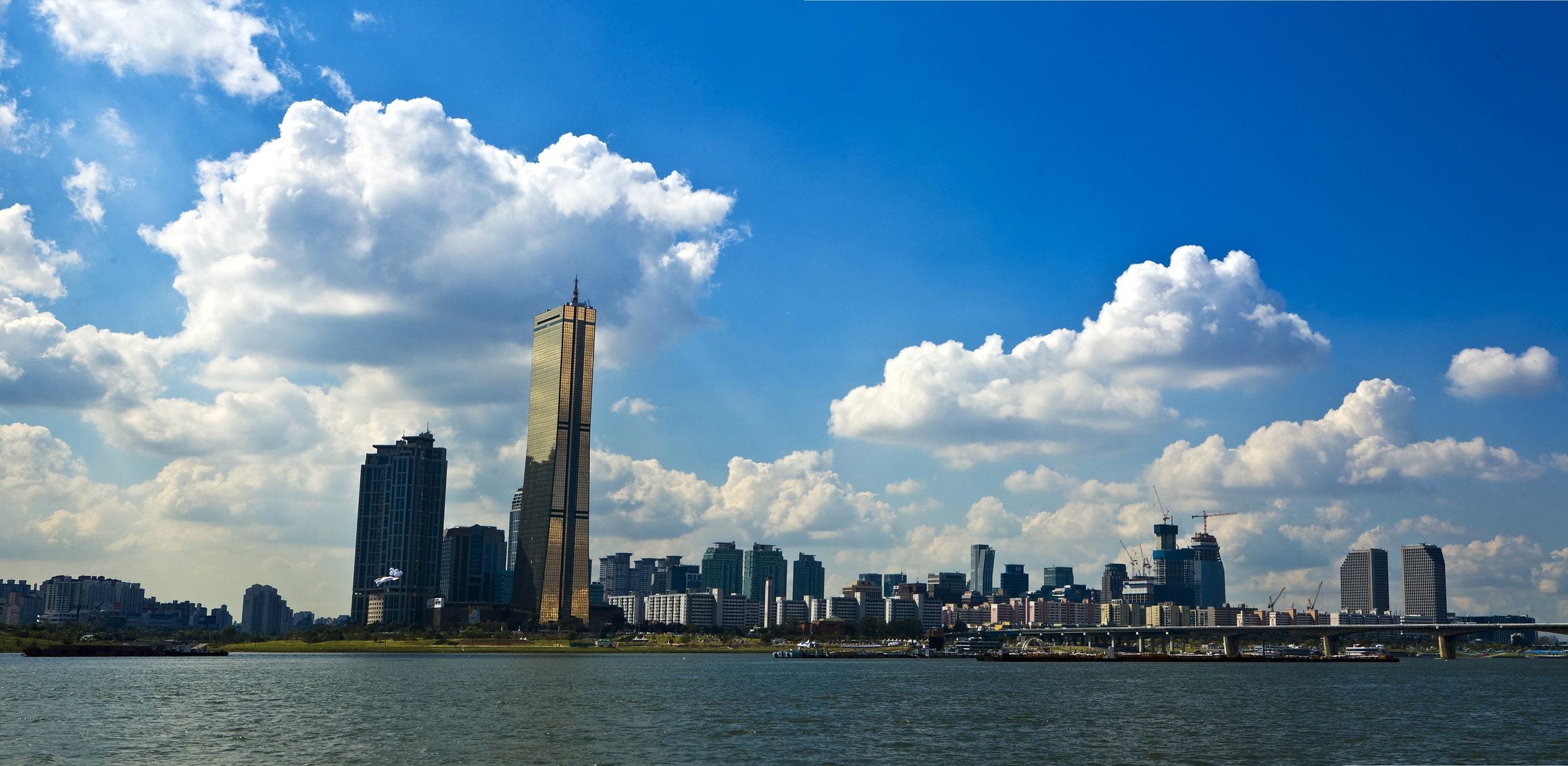 The Han River on a bright day with the Yeouido skyline and the golden 63 Building rising behind the water