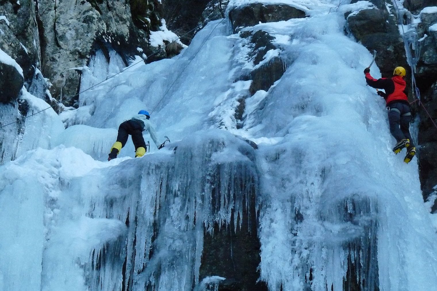 Boyana Waterfall on Vitosha frozen into ice in winter, with two climbers on it, Bulgaria