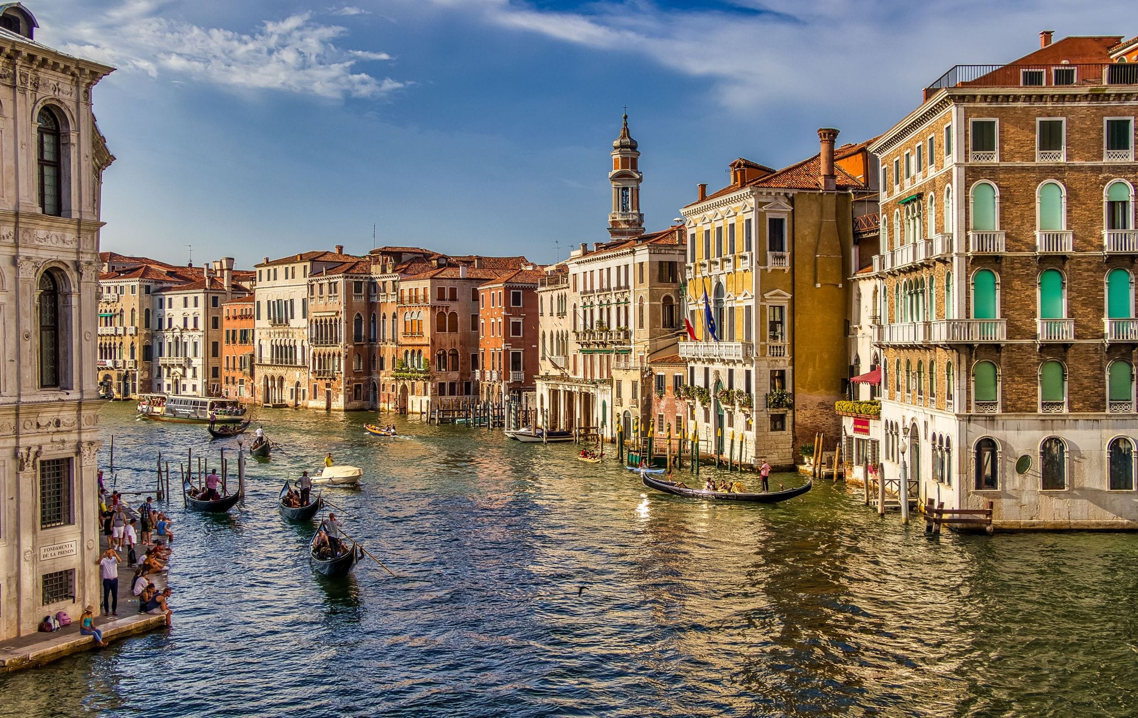 Palazzi lit at dusk along the Grand Canal in Venice, their windows reflected in the still water